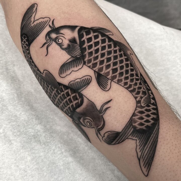 Dos carpas koi nadando en sentidos opuestos, con las escamas sombreadas, tatuadas en la pierna.