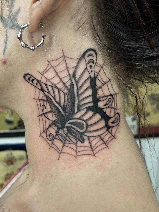 Golondrina en picado sobre una telaraña, tatuada en el lateral del cuello en negro y gris.