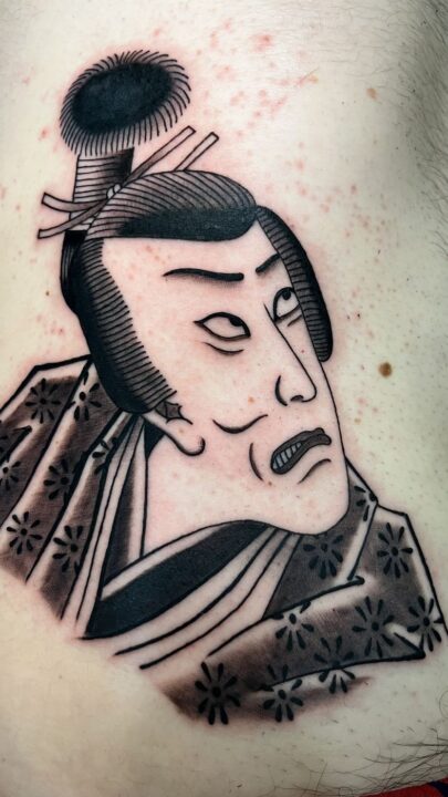Retrato de un actor de kabuki con moño alto y kimono estampado, tatuado en el costado.