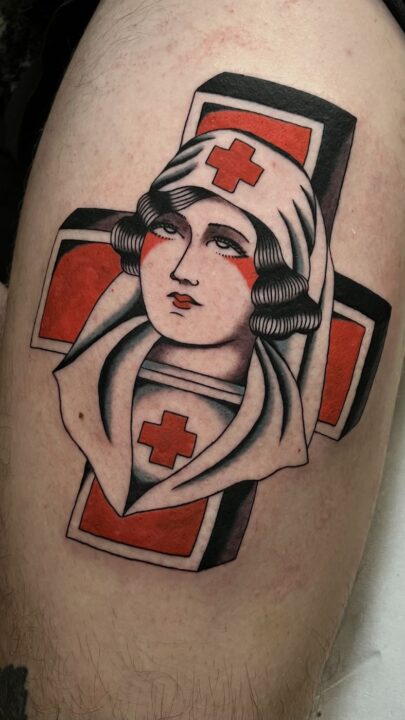 Enfermera con cofia sobre una cruz roja de fondo, tatuada en el muslo en rojo, negro y gris.