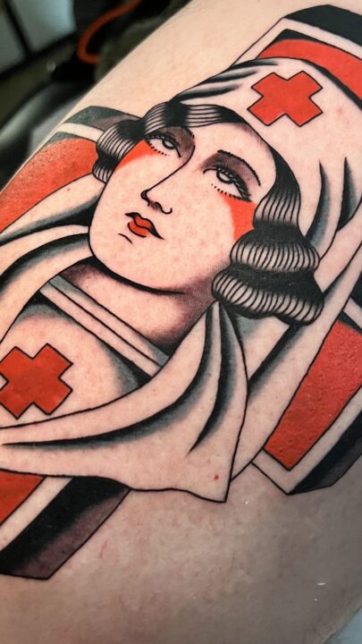 Detalle del rostro de la enfermera: rubor, labios rojos y rizos negros sobre la cruz roja.