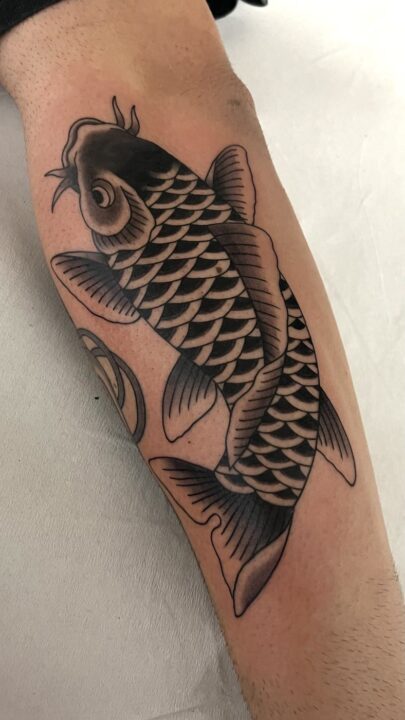 Carpa koi de escamas sombreadas nadando hacia arriba, tatuada en el antebrazo.