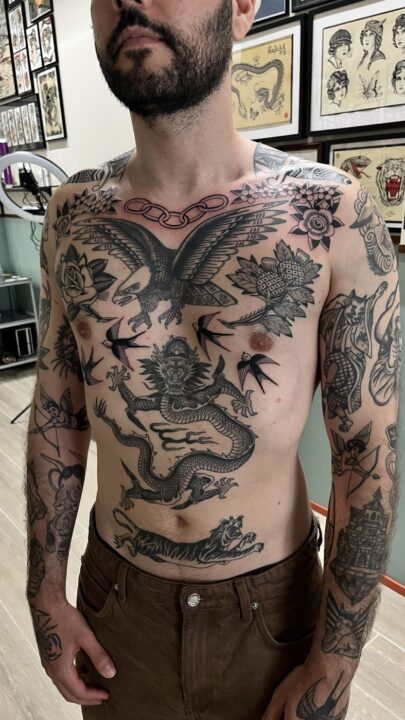 Torso entero tatuado: águila con las alas abiertas en el pecho, dragón en el vientre, golondrinas y un tigre.